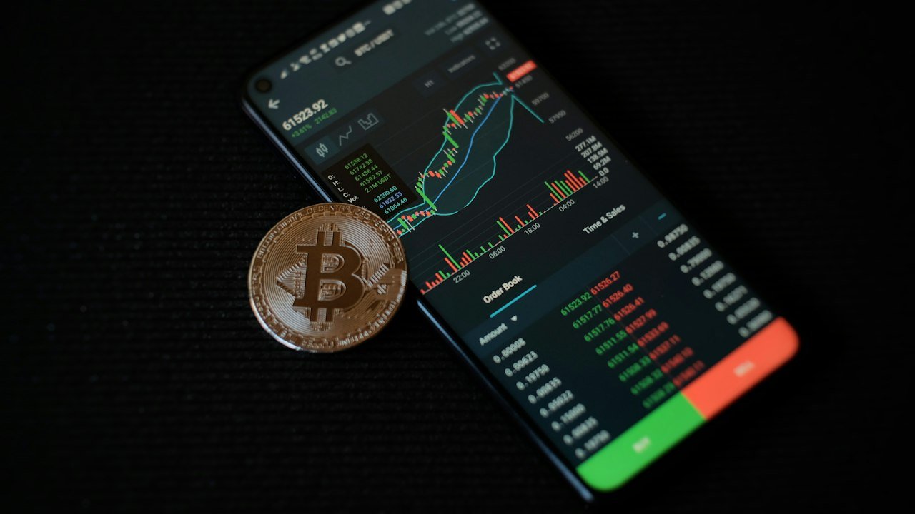 Bitcoin coin on a smartphone, comparing crypto with stocks