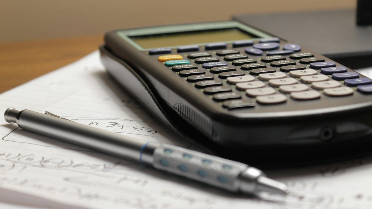 Calculator and pen on paper used to compare CD vs high yield savings account returns