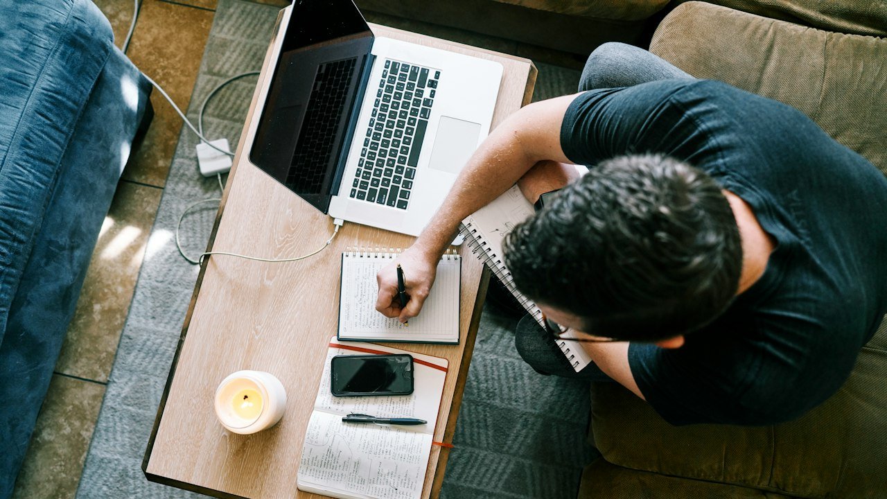 Man working on a laptop at a table while using Claude AI for a project