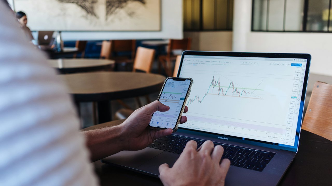 Person using a laptop and phone to manage a stocks and shares ISA