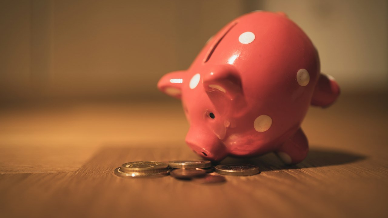 Pink pig coin bank on a wooden table representing a CD vs high yield savings account choice