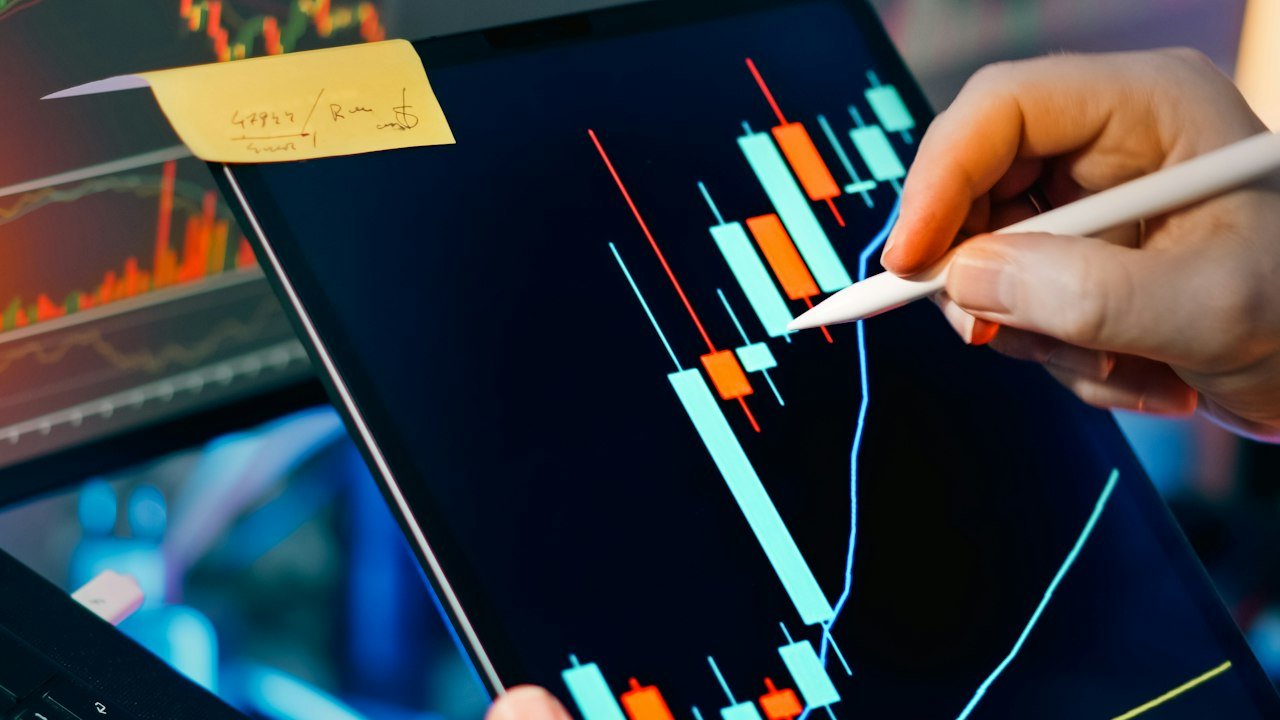 Trader reading candlestick patterns for day trading on a tablet and monitor